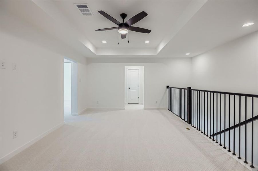 Spare room featuring light carpet, recessed lighting, ceiling fan, and a raised ceiling