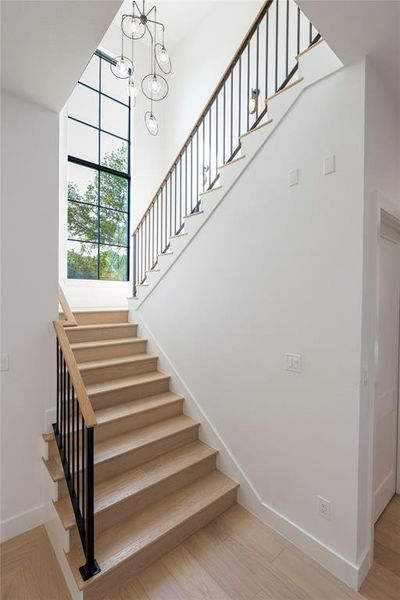 Staircase featuring wood-type flooring and a chandelier