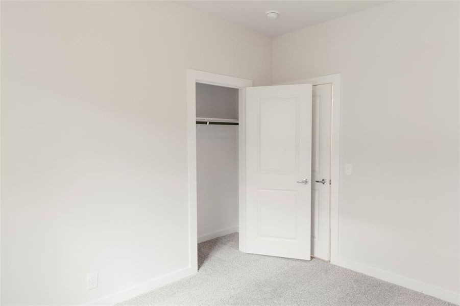 Unfurnished bedroom featuring light carpet and a closet