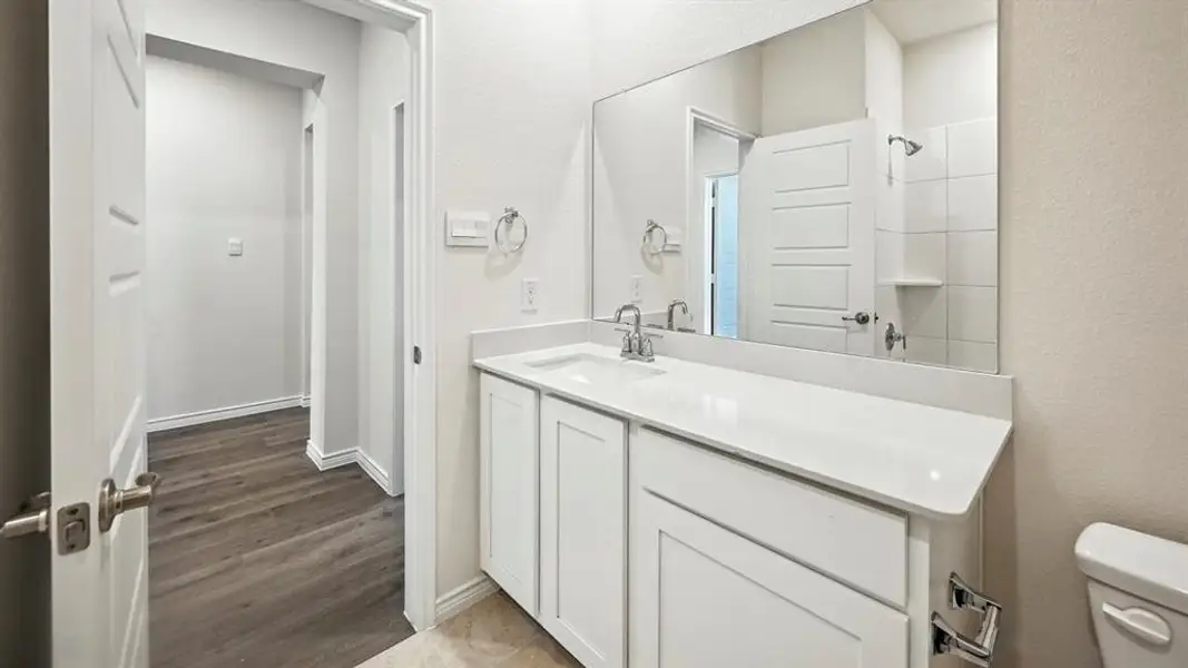 Bathroom featuring a white vanity with integrated sink, chrome fixtures, and a large wall-mounted mirror