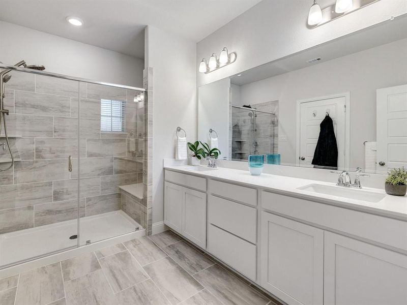 The luxurious frameless glass shower enclosure features a built-in bench seat and is upgraded with dual spray heads for an immersive, resort-style bathing experience.