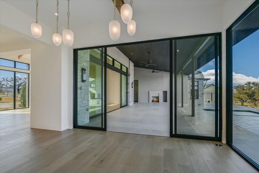 Entryway featuring a lit fireplace, wood finished floors, expansive windows, and a ceiling fan
