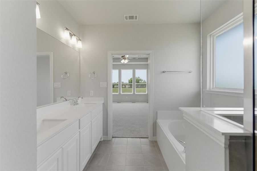 Bathroom featuring a dual vanity with white cabinetry, a large mirror, and a built-in bathtub with a tiled surround Bathroom featuring a dual vanity with white cabinetry, a large mirror, and a built-in bathtub with a tiled surround