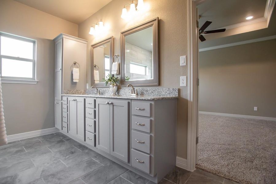 Bathroom with double vanity, a ceiling fan, a sink, baseboards, and ornamental molding