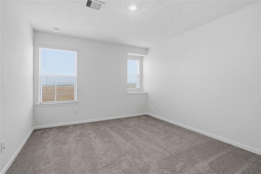 Well appointed secondary bedroom that features plush carpeting, neutral paint tones, recessed lighting, large window, and a generously sized closet.