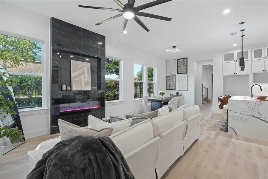 Living room featuring ceiling fan, plenty of natural light, light wood finished floors, recessed lighting, and a fireplace