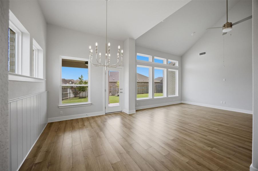 A spacious room features vaulted ceilings and wide plank flooring, offering ample natural light.