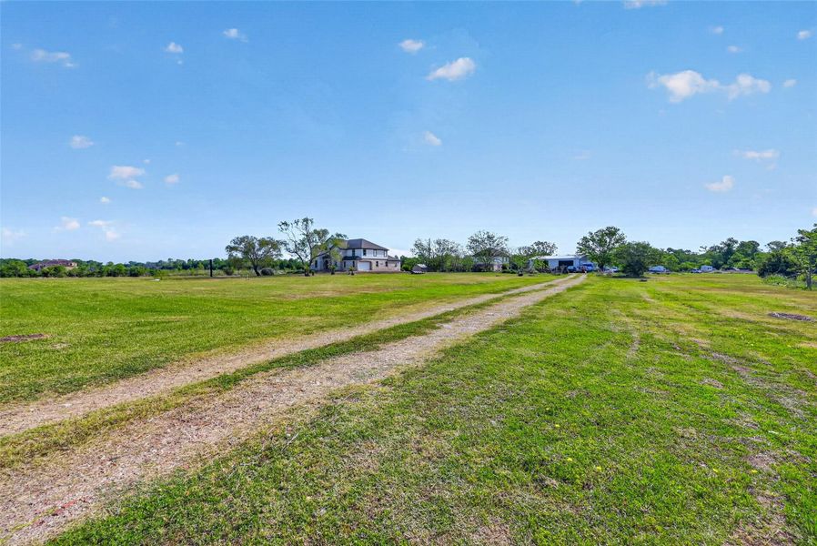 Drive approach through the property showcasing expansive open land and rural surroundings.