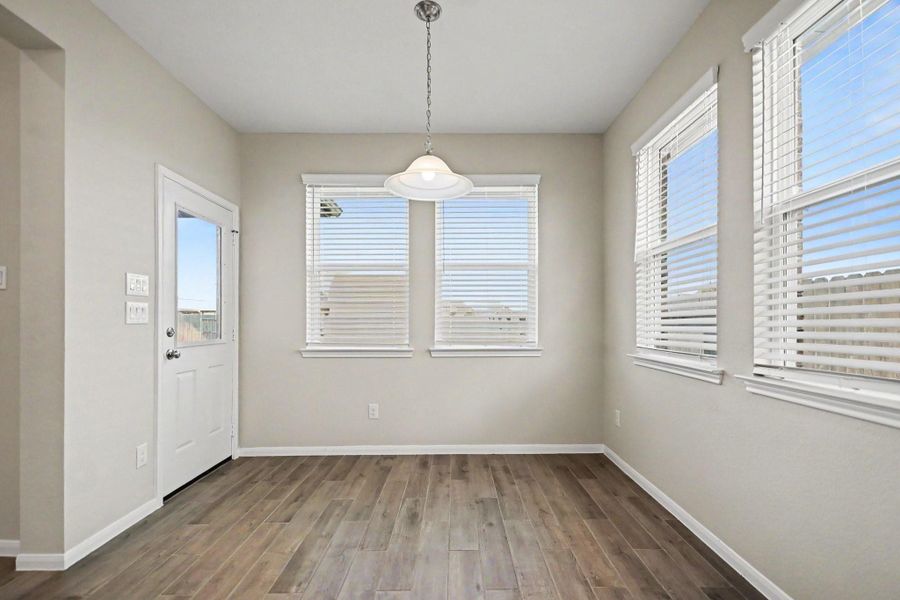 Bright and inviting breakfast nook with large windows, sleek wood flooring, and a modern light fixture, perfect for enjoying morning meals.