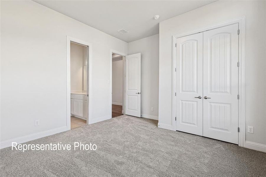 Unfurnished bedroom with a closet, light colored carpet, and ensuite bathroom