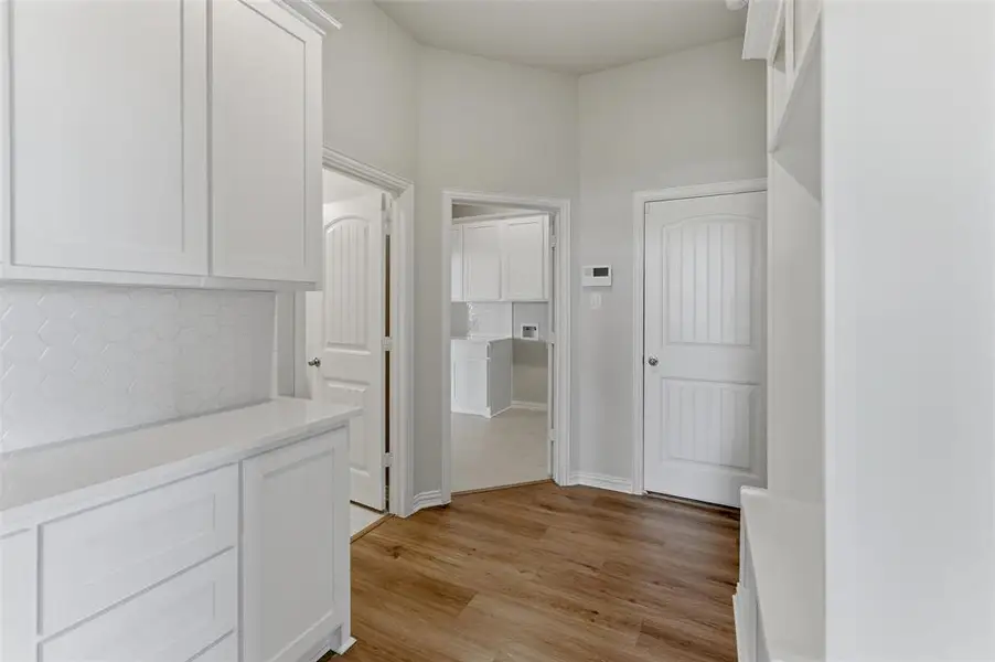 The property features white cabinetry with a hexagonal tile backsplash, light wood-style flooring, and white interior doors