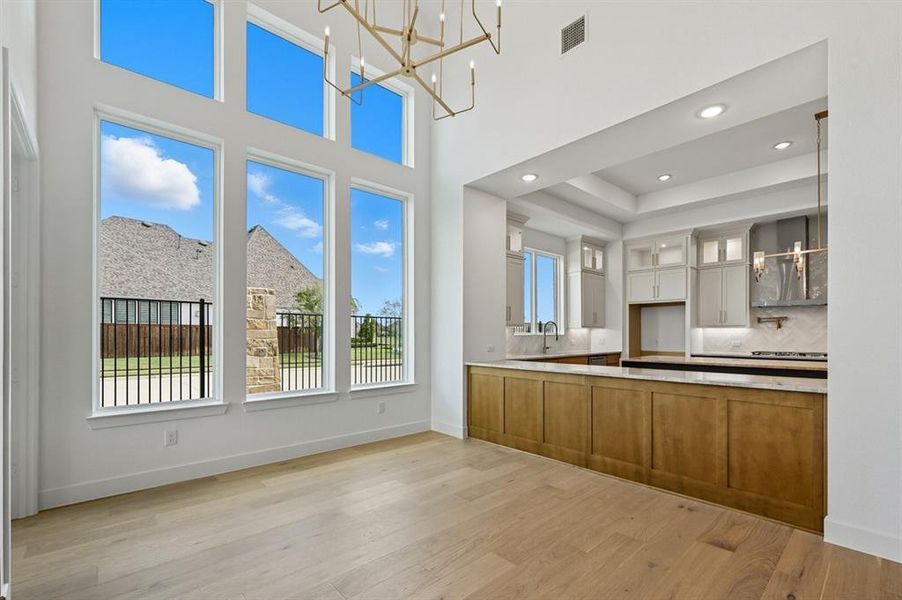 Kitchen with glass insert cabinets, tasteful backsplash, light wood finished floors, plenty of natural light, and a towering ceiling Kitchen with glass insert cabinets, tasteful backsplash, light wood finished floors, plenty of natural light, and a towering ceiling