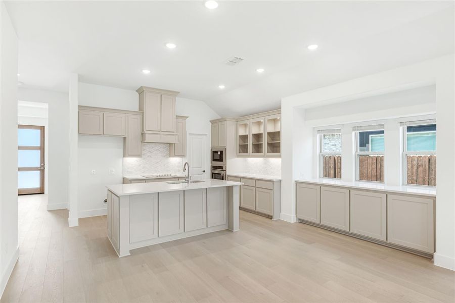 Open kitchen with gray cabinets, center island, white countertops, and light hardwood floors