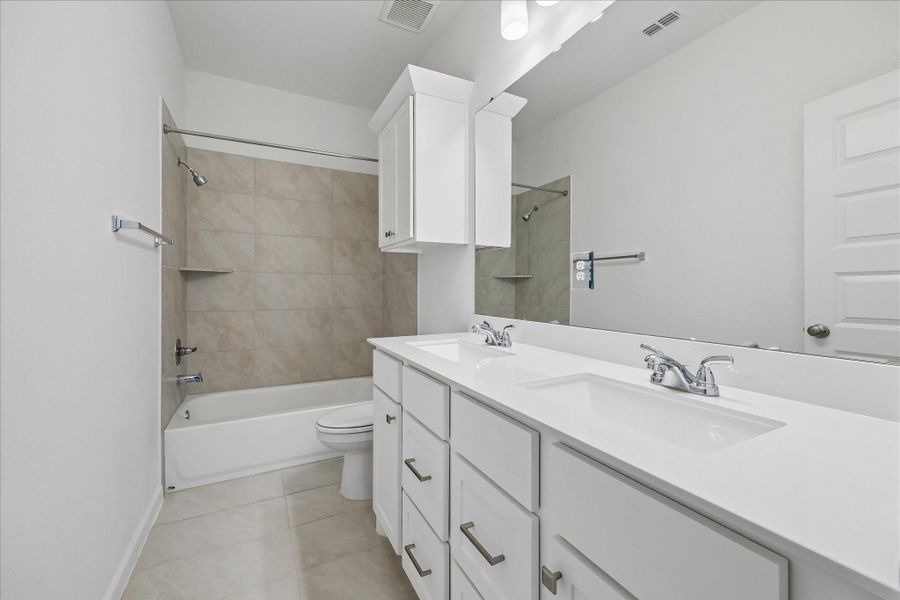 The upstairs full bathroom is easy to share with an extended dual-sink vanity that offers plenty of elbow room and storage. A tiled tub and shower enclosure adds everyday function for the two nearby bedrooms.