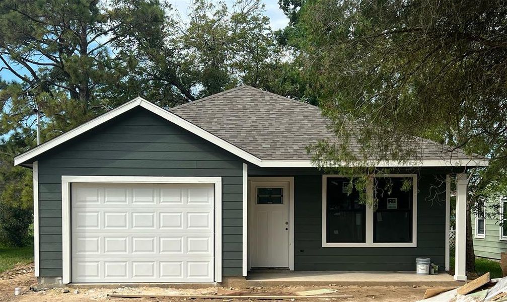 This is a newly constructed single-story home featuring a dark green siding exterior and a covered front entrance.