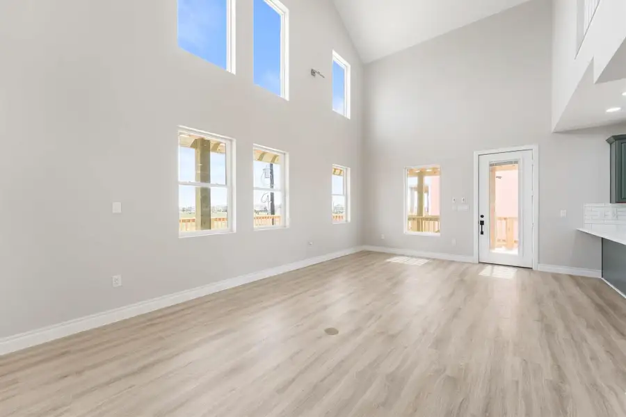 Bright and spacious living area with high ceilings and abundant natural light. Features large windows, modern wood flooring, and a door leading to an outdoor space. Perfect for open concept living. Bright and spacious living area with high ceilings and abundant natural light. Features large windows, modern wood flooring, and a door leading to an outdoor space. Perfect for open concept living.