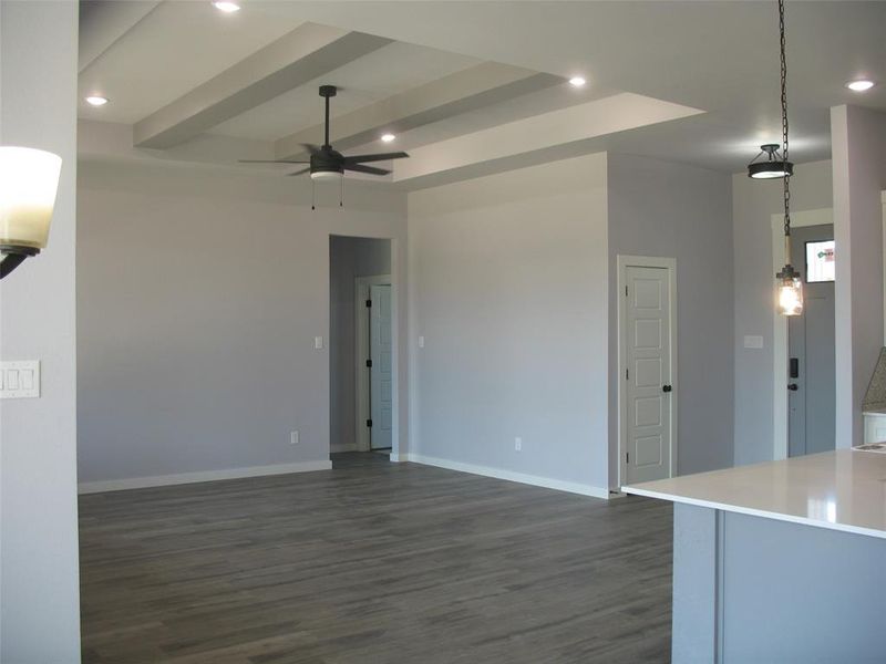 Unfurnished living room featuring beamed ceiling, dark wood-style flooring, recessed lighting, and ceiling fan