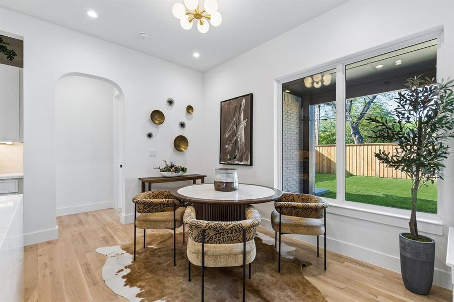 Dining area with arched walkways, light wood-type flooring, and a chandelier