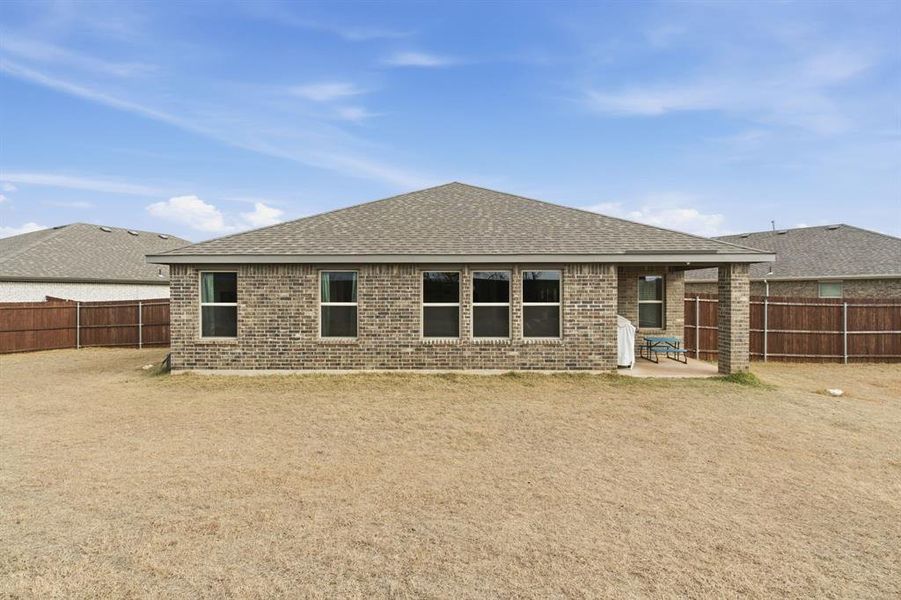 Back of property with roof with shingles, a patio, brick siding, and a fenced backyard