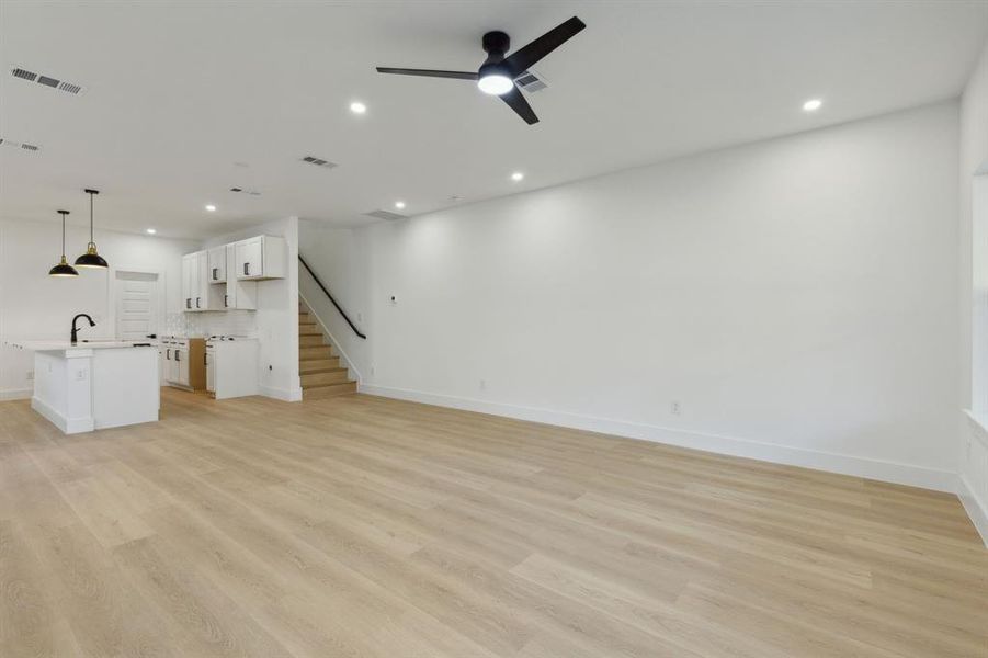 Unfurnished living room with sink, light wood-type flooring, and ceiling fan