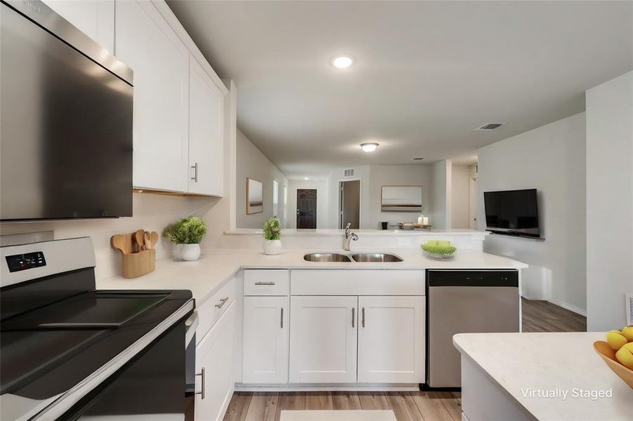 Kitchen with kitchen peninsula,sink, white cabinets, and appliances with stainless steel finishes