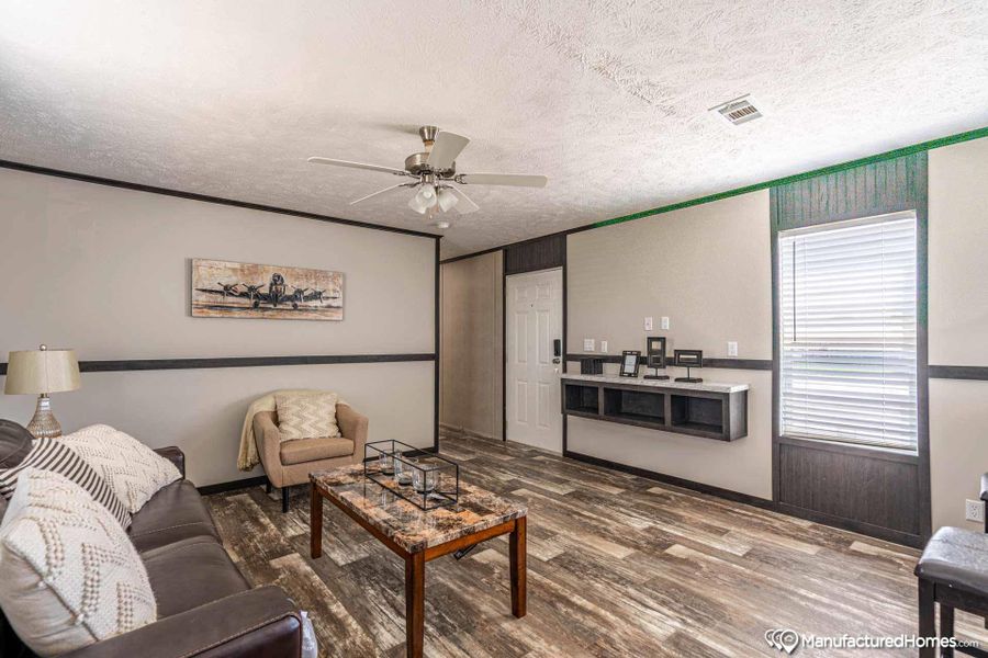 A comfortable living space boasts durable laminate flooring, a ceiling fan, and a convenient built-in shelf.