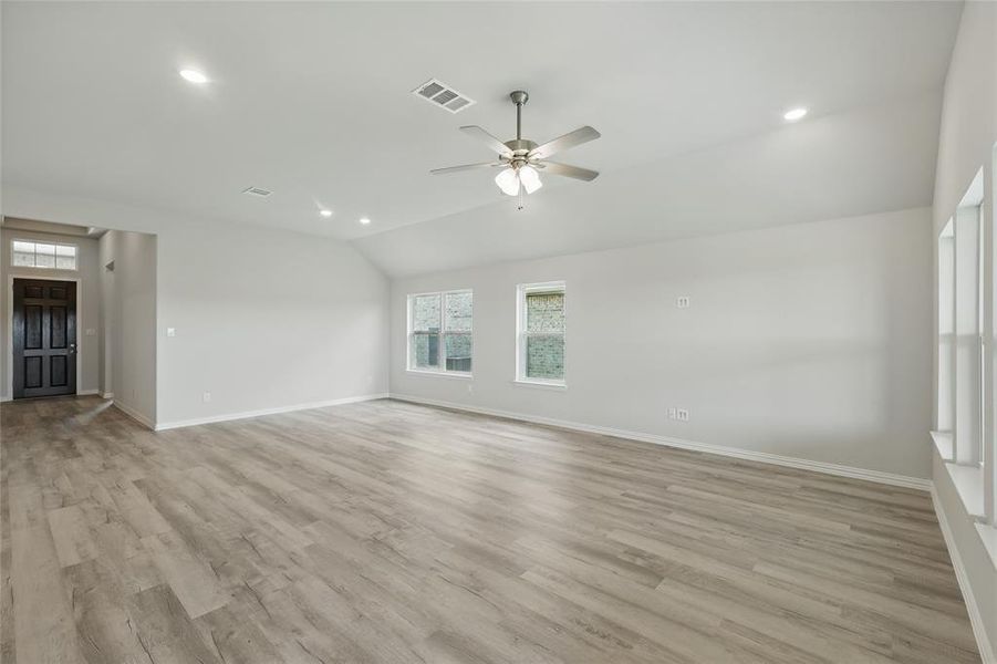 Unfurnished living room with lofted ceiling, baseboards, a ceiling fan, light wood-style flooring, and recessed lighting Unfurnished living room with lofted ceiling, baseboards, a ceiling fan, light wood-style flooring, and recessed lighting
