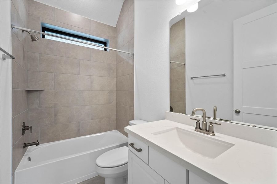 This well-appointed secondary bathroom offers exceptional functionality with its bright white cabinet, light countertop and convenient undermount sink. The tub shower combination with tile surround and built in shelf are all finished with sleek, polished fixtures.