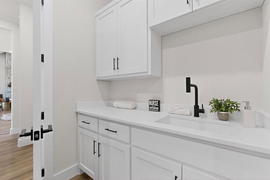 Bar with white cabinetry and light wood finished floors