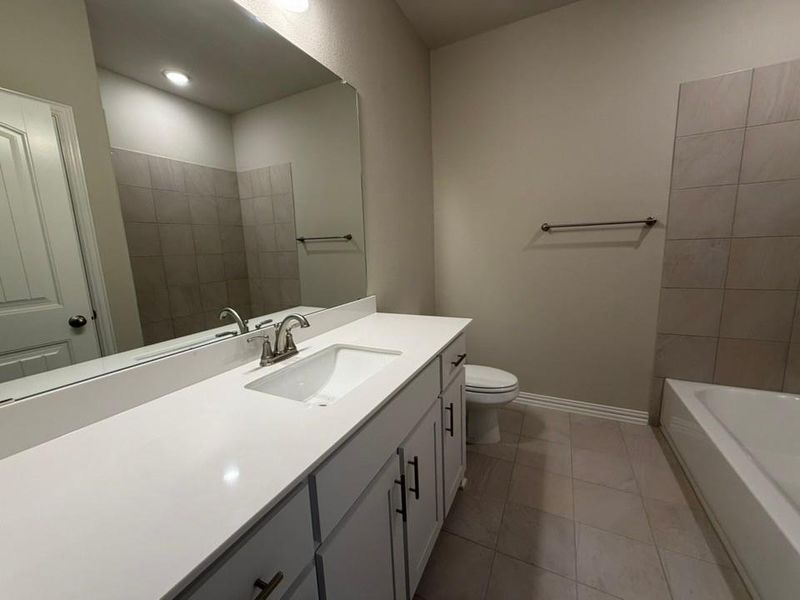 Bathroom featuring a long vanity with a white countertop, an integrated sink, and brushed nickel fixtures