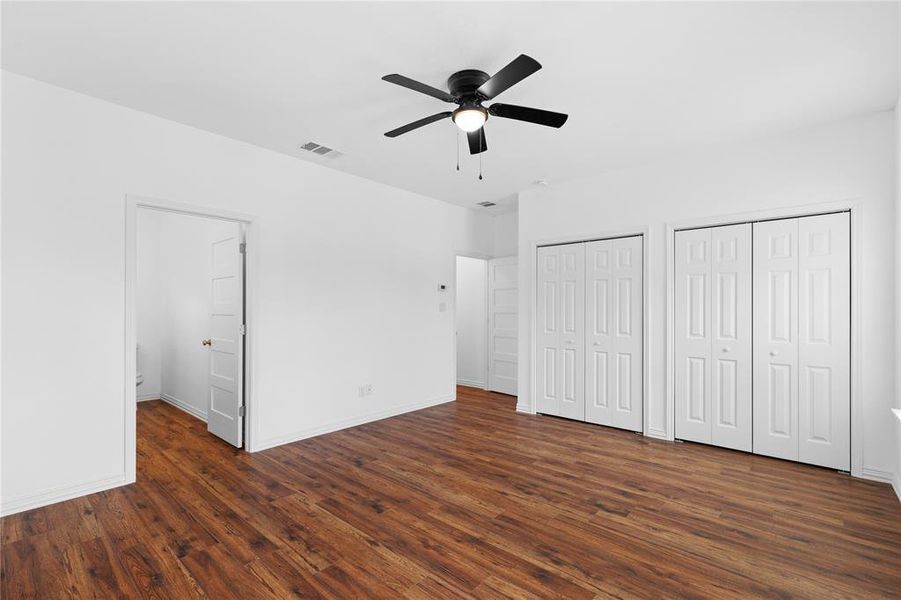 Unfurnished bedroom with two closets, a ceiling fan, and dark wood-style flooring Unfurnished bedroom with two closets, a ceiling fan, and dark wood-style flooring