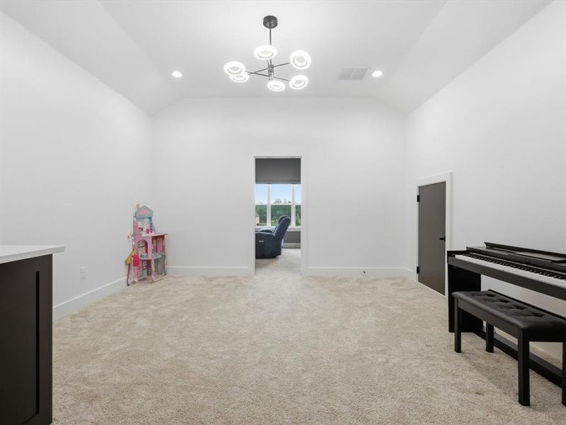 Bonus room on second level, featuring a modern chandelier, recessed lighting, and a vaulted ceiling