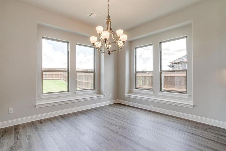 Unfurnished room featuring hardwood / wood-style flooring and an inviting chandelier