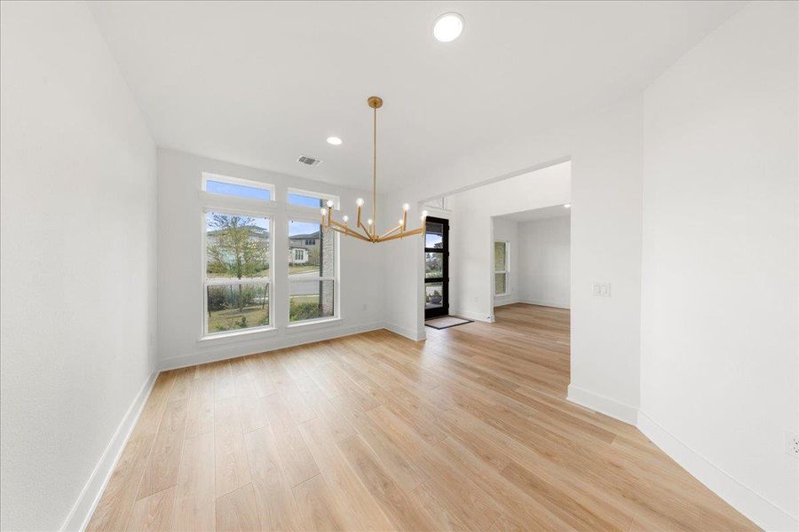 Unfurnished dining area featuring light wood finished floors, a chandelier, and recessed lighting Unfurnished dining area featuring light wood finished floors, a chandelier, and recessed lighting