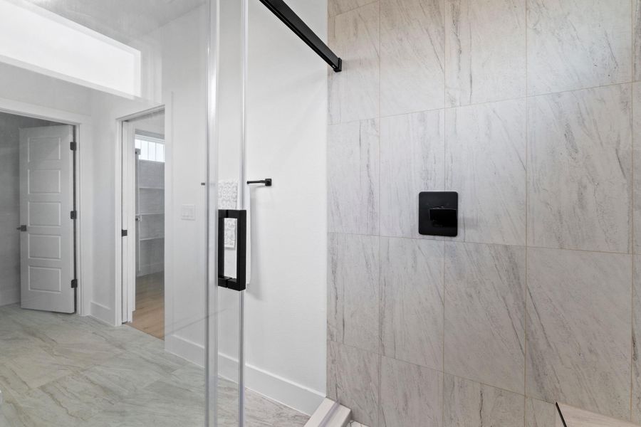 Gleaming tile floors and a glass-enclosed shower highlight this modern bathroom space.