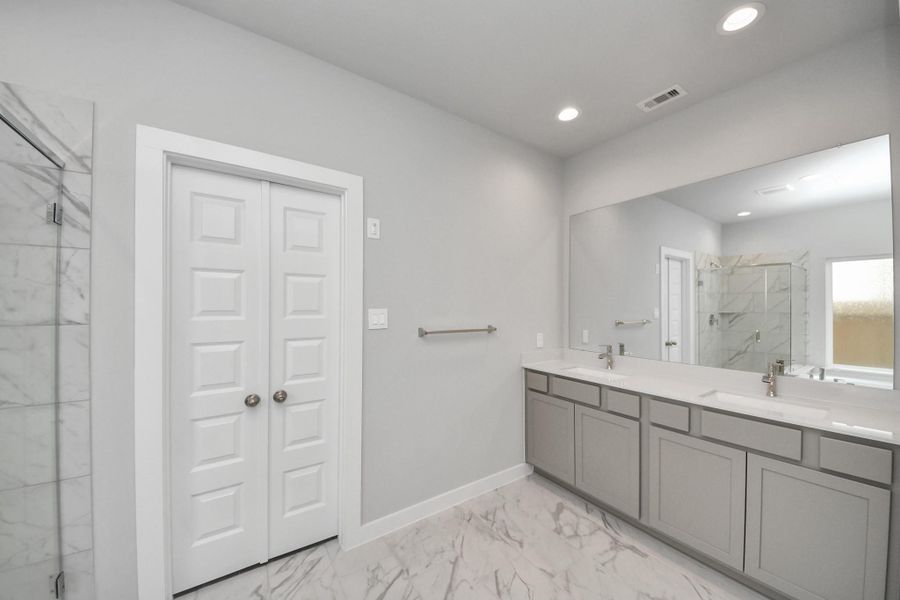 Elevate your daily routine at the elegant vanity, now equipped with double sinks, light countertops, modern hardware, and beautiful recessed lights. Sample photo of completed home with similar floor plan. Actual colors and selections may vary.