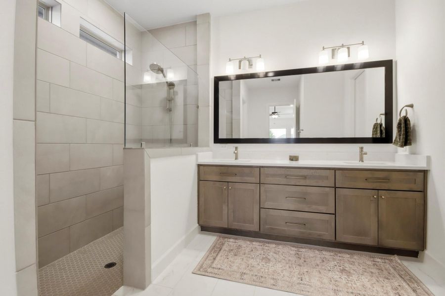 Modern bathroom featuring a spacious walk-in shower, dual sinks with ample storage, and elegant lighting.