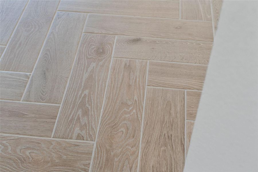The photo highlights the wood-look tile in a herringbone layout, which flows throughout this gorgeous home.