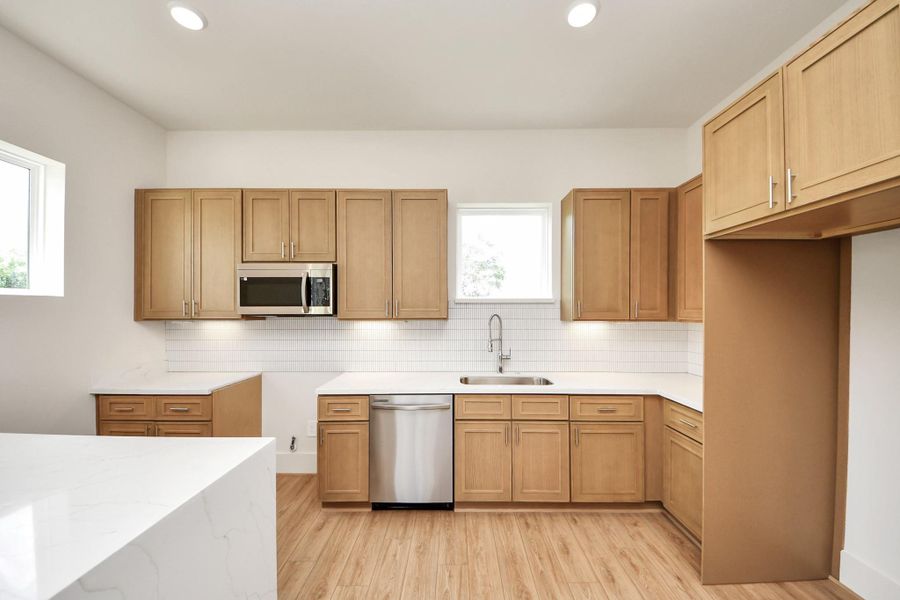 The MB3 Floorplan – KitchenThis bright kitchen features warm wood cabinetry, sleek quartz countertops, and stainless steel appliances. Thoughtfully designed with ample storage, a spacious layout, and modern finishes, it’s both functional and stylish.