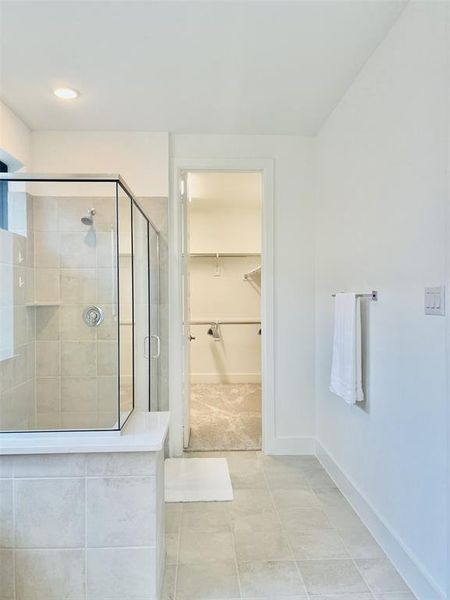 Bathroom with a stall shower, a walk in closet, light tile patterned floors, and recessed lighting Bathroom with a stall shower, a walk in closet, light tile patterned floors, and recessed lighting