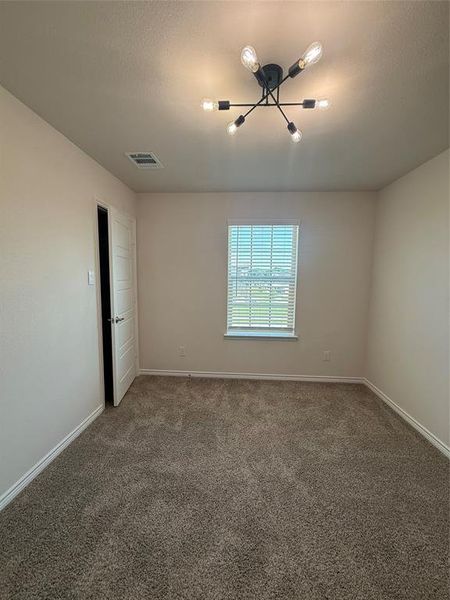 Neutral-toned room featuring a modern black sputnik-style ceiling light fixture, a window with horizontal blinds, and plush carpet flooring