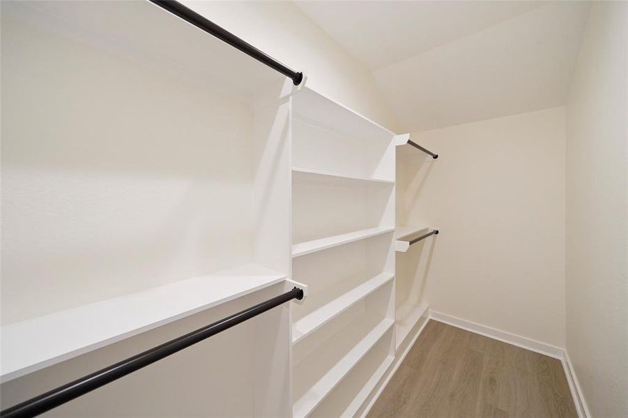 Primary closet with hanging space and built in shelves for storage.