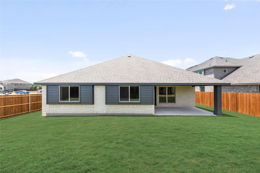 Rear exterior of single-story home with brick and blue siding, covered patio, and fenced backyard Rear exterior of single-story home with brick and blue siding, covered patio, and fenced backyard