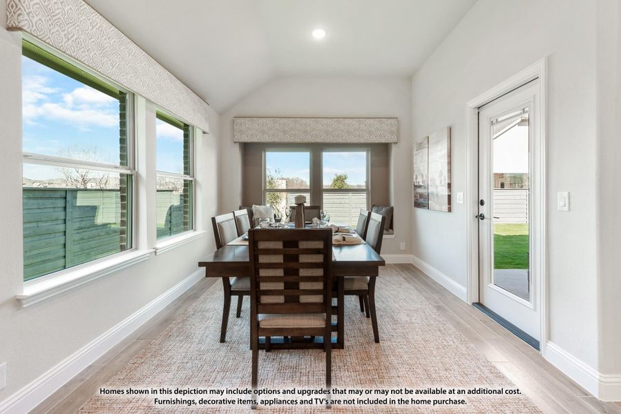 Dining room with dark wood table and chairs, vaulted ceiling, large windows, and glass door to backyard