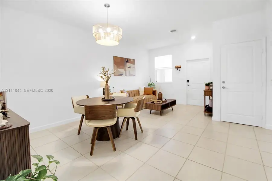 Large-format tile flooring, drum-style chandelier with metallic finish, crisp white wall palette, and six-panel interior door Large-format tile flooring, drum-style chandelier with metallic finish, crisp white wall palette, and six-panel interior door