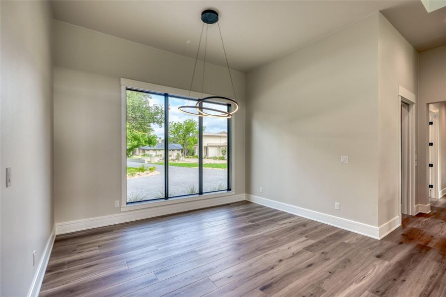 Unfurnished dining area featuring wood finished floors, baseboards, and a chandelier