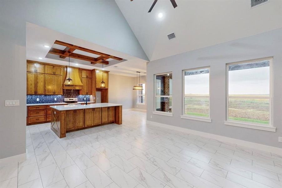 Kitchen with a center island with sink, tasteful backsplash, stainless steel range with electric cooktop, custom range hood, and pendant lighting