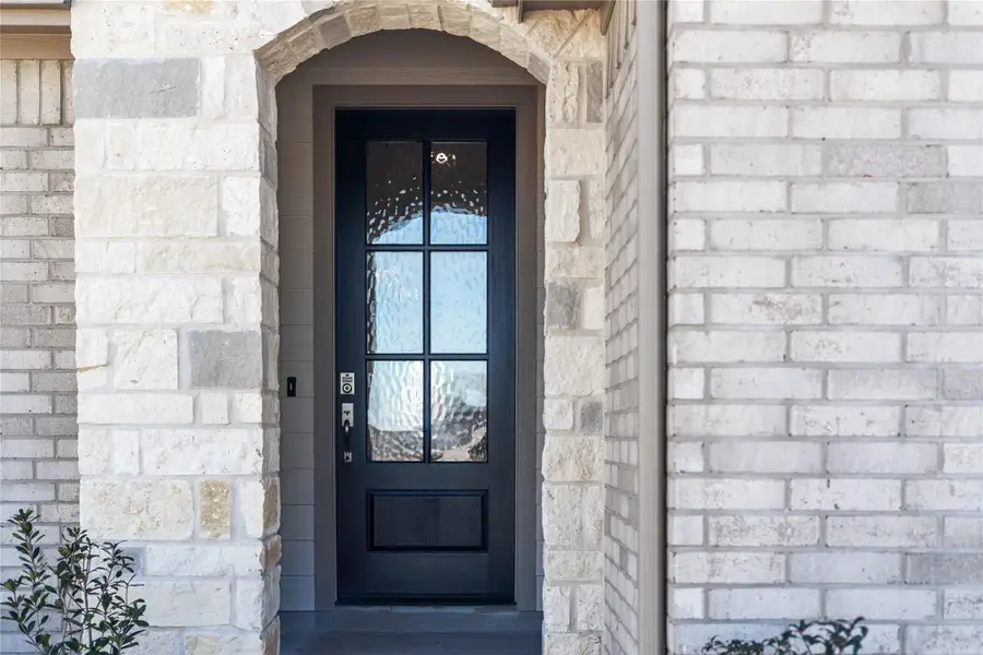 Exceptional curb appeal defines this residence. It features an arched stone entry and a gorgeous six-lite door with glass panes making it the focal point for this modern farmhouse entryway.