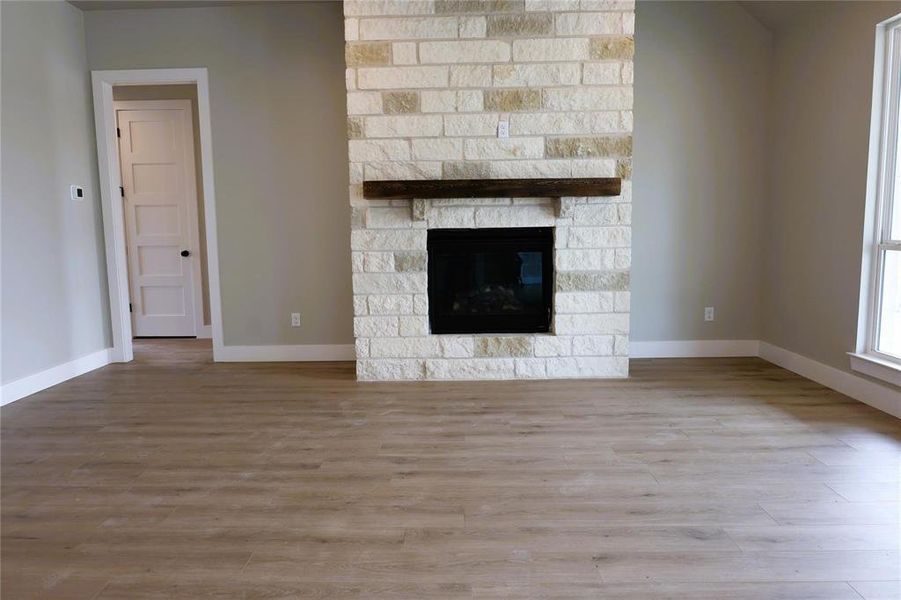 Unfurnished living room with a stone fireplace and hardwood / wood-style floors