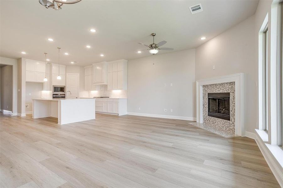 Unfurnished living room with sink, ceiling fan, and light hardwood / wood-style floors